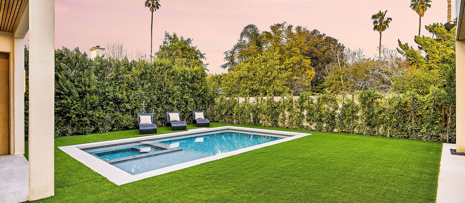 Backyard pool with lounge chairs and greenery.